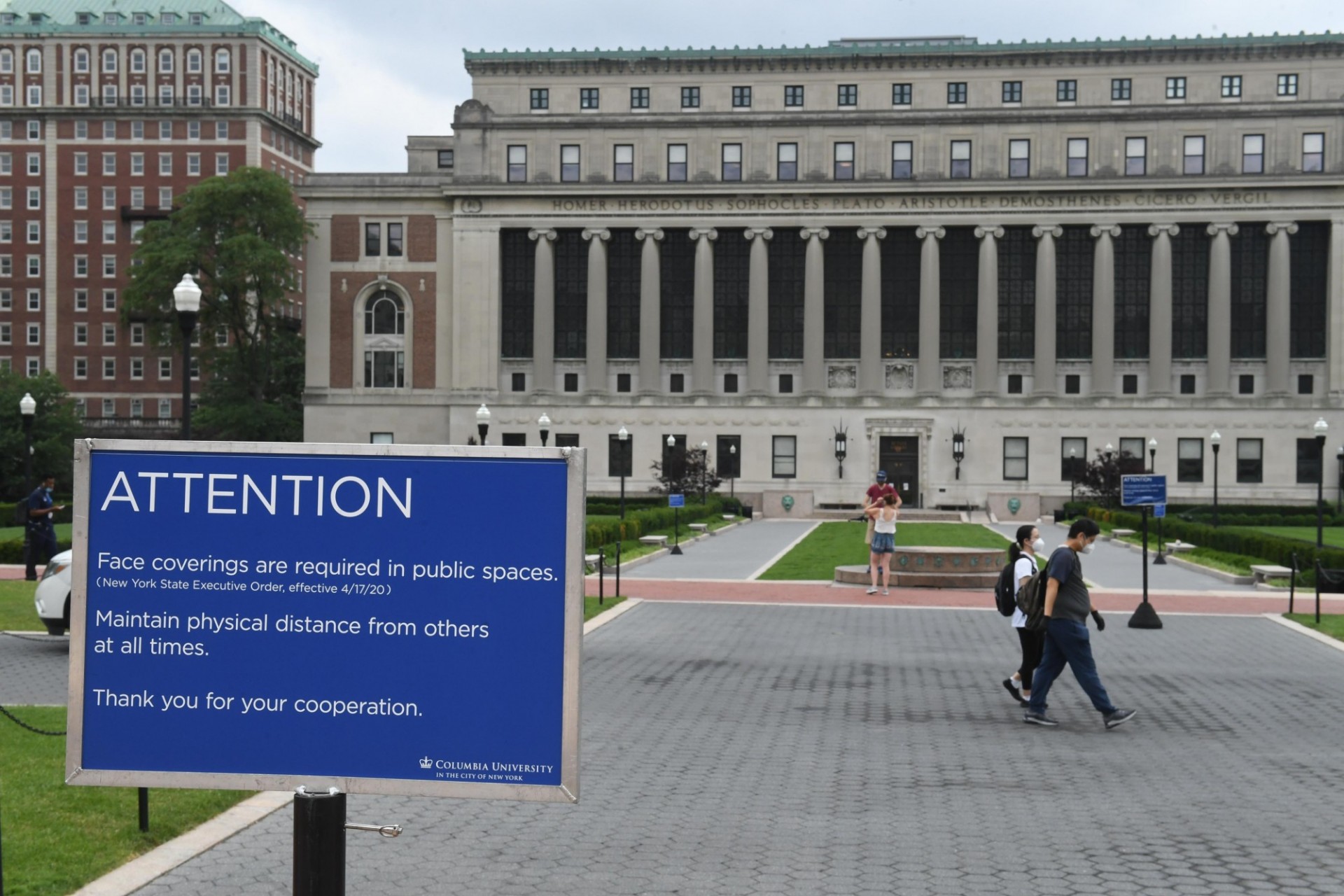A sign in front of Columbia University's Butler library warns that face coverings are required in public spaces and that social distancing must be maintained. 