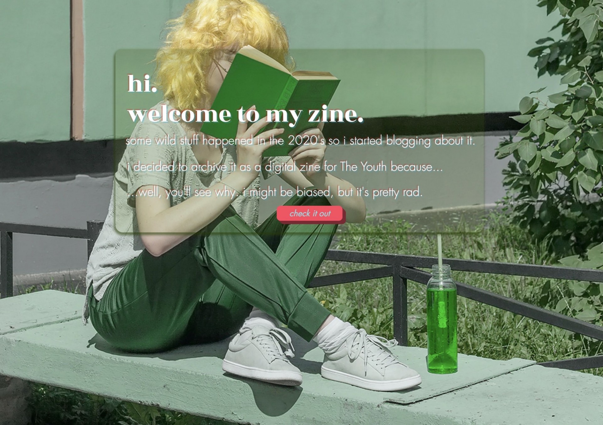 A blonde person's face is hidden by a book she is ready while sitting outside. They are dressed in all green and a water bottle filled with green liquid is next to them. 