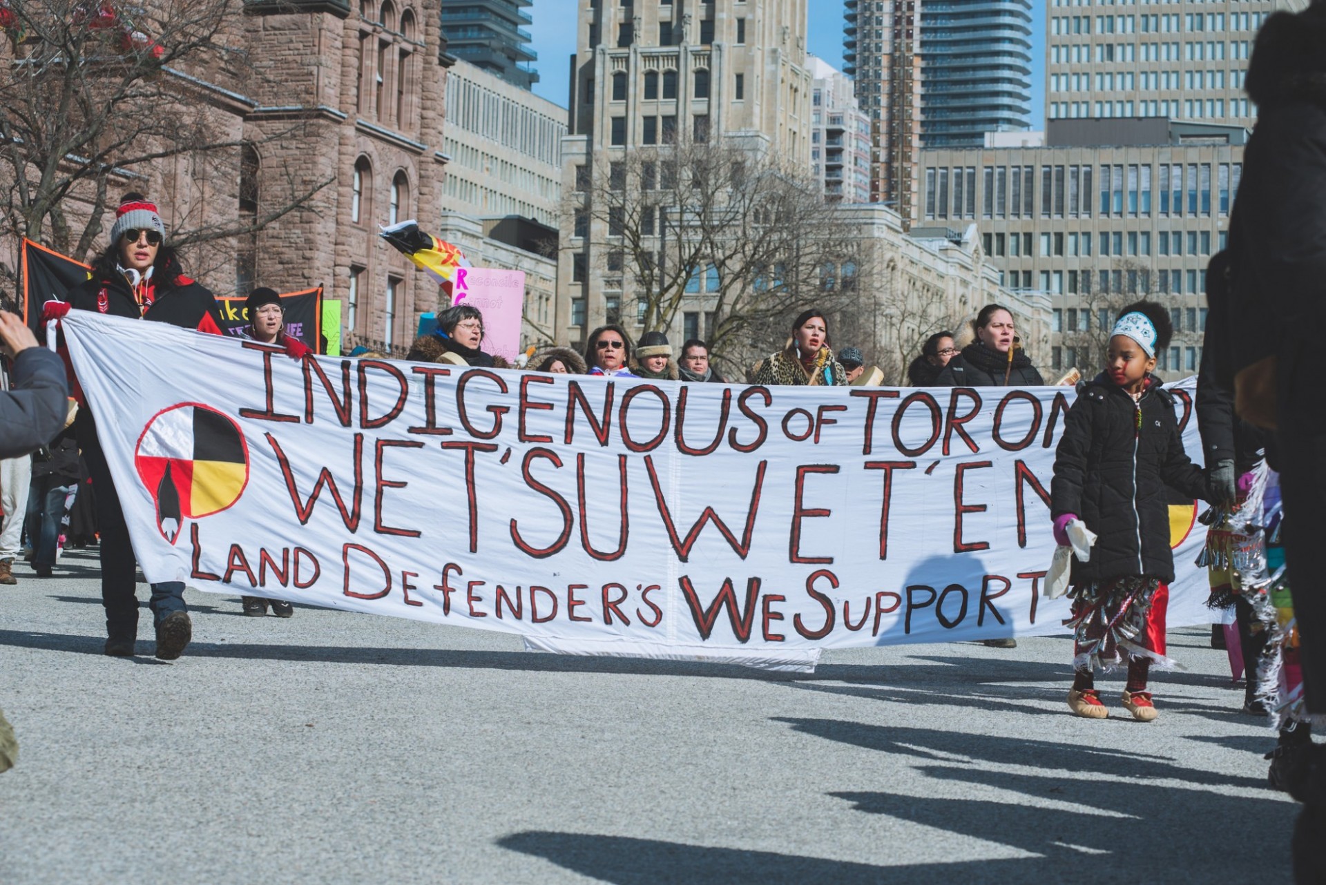 Protestors walk down the street with large banner in Toronto during the Wet’suwet’en Nation protests